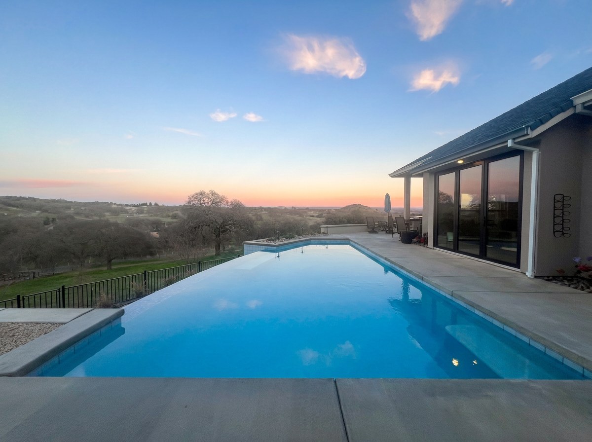 Custom infinity edge pool at sunset overlooking rolling hills